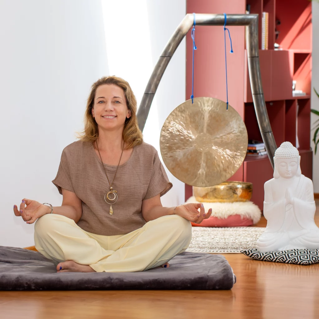 Karin Neuhofer sitzt vor dem Gong und Buddha